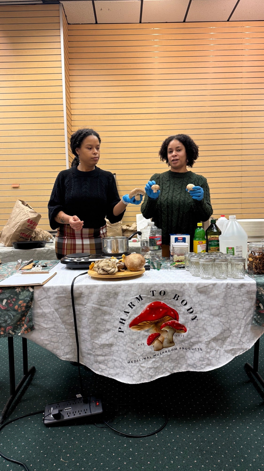 Pharm to Body co-founders leading a mushroom workshop with jars, samples, and a branded tablecloth